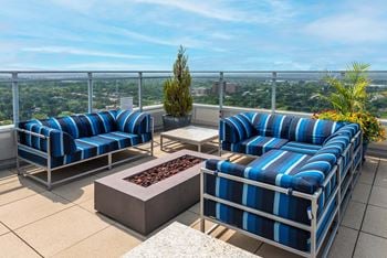 A patio with blue and white striped couches and a fire pit.